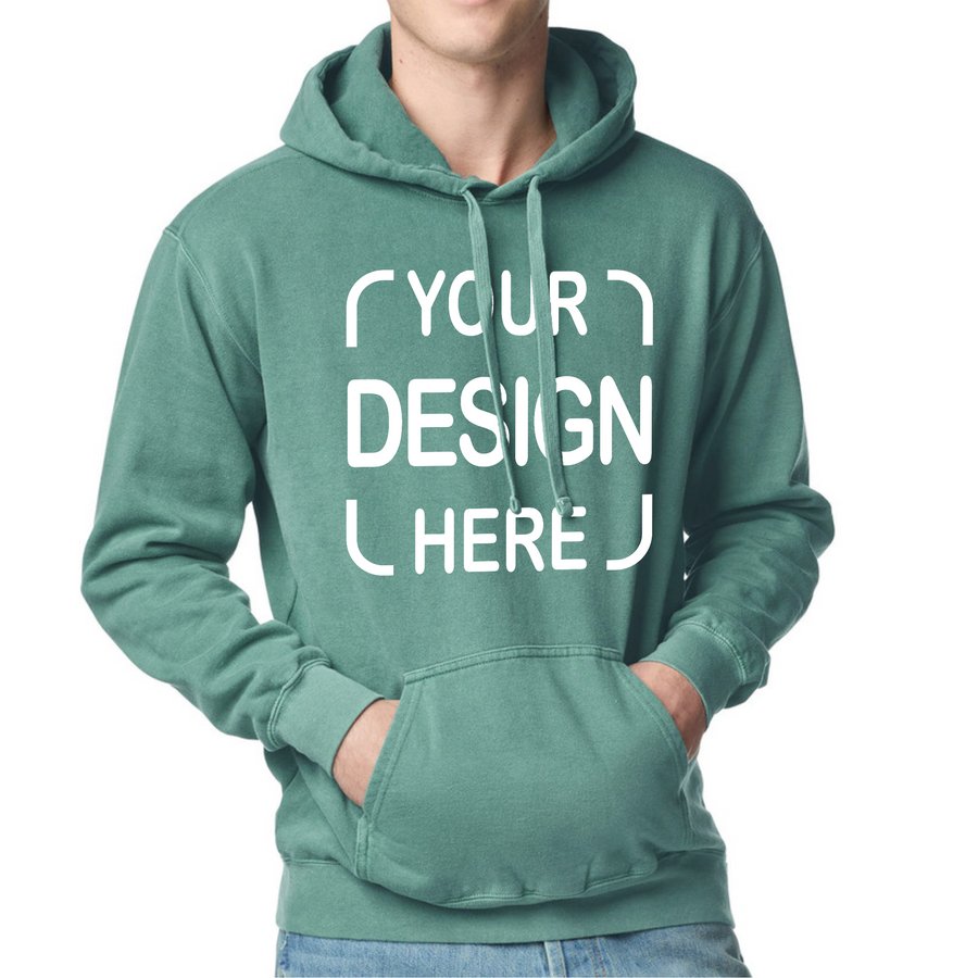A person wearing a sage green pullover hoodie with a white customizable text graphic reading 'YOUR DESIGN HERE' on the front