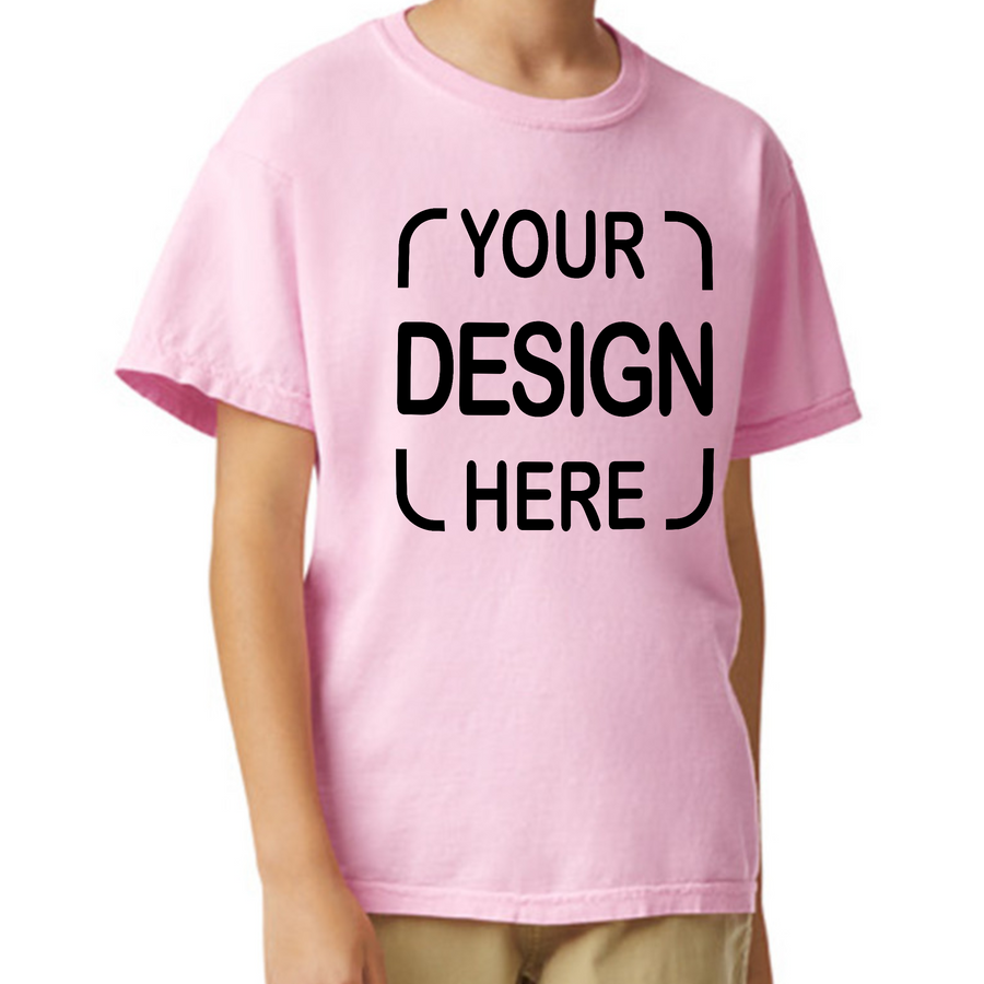 A child wearing a light pink short-sleeve t-shirt with black placeholder text reading 'YOUR DESIGN HERE' on the front
