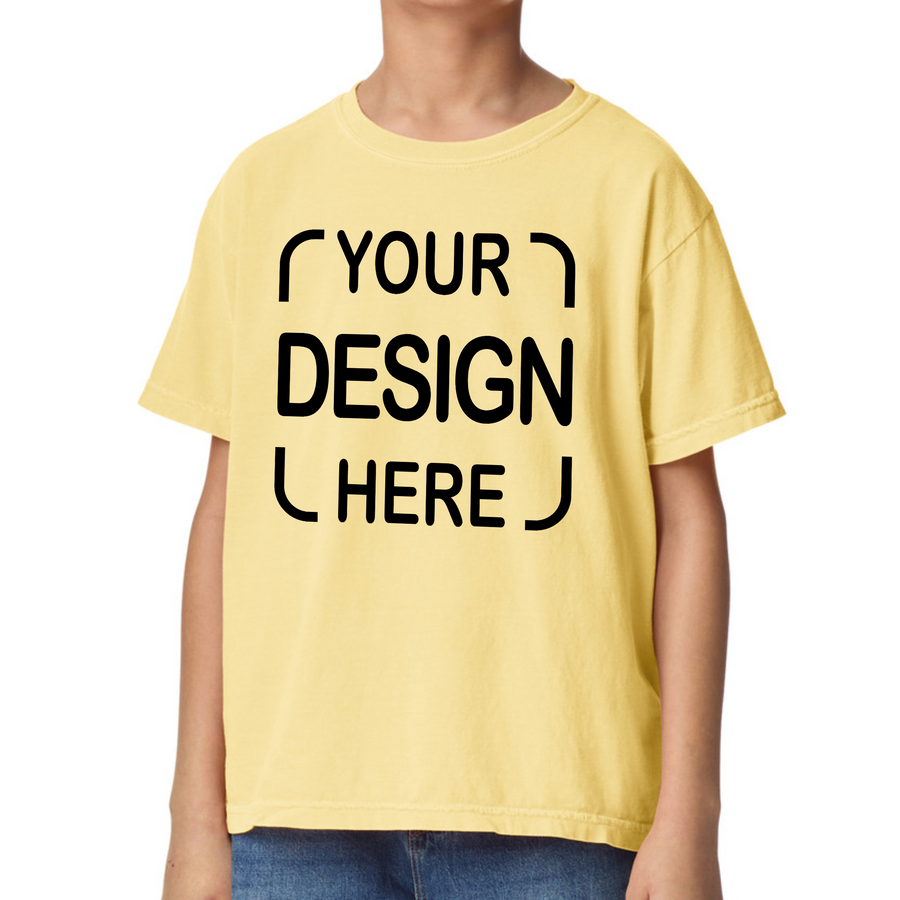 A child wearing a pale yellow short-sleeve T-shirt with black placeholder text reading 'YOUR DESIGN HERE' on the front