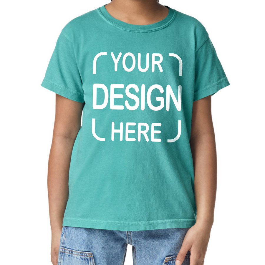 A child wearing a teal short-sleeve t-shirt with white placeholder text reading 'YOUR DESIGN HERE' on the front